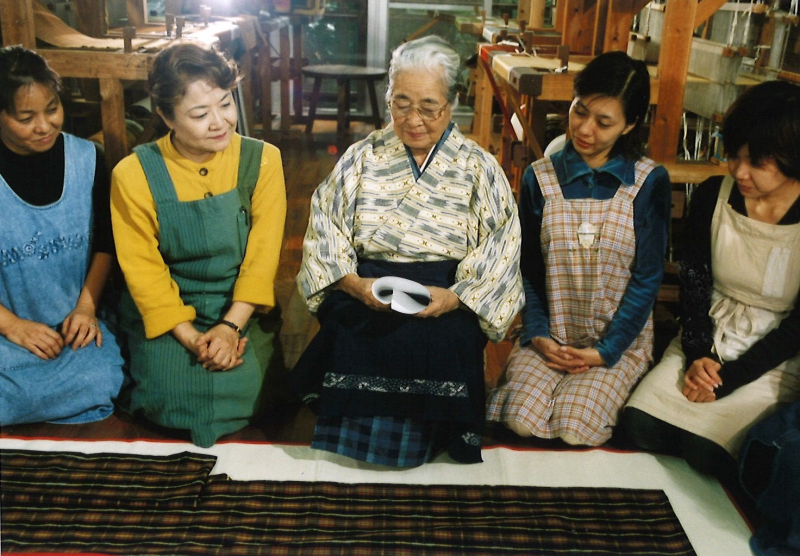 完成した衣裳を前に「手縞織唄」を歌う宮平と工房の女性たち